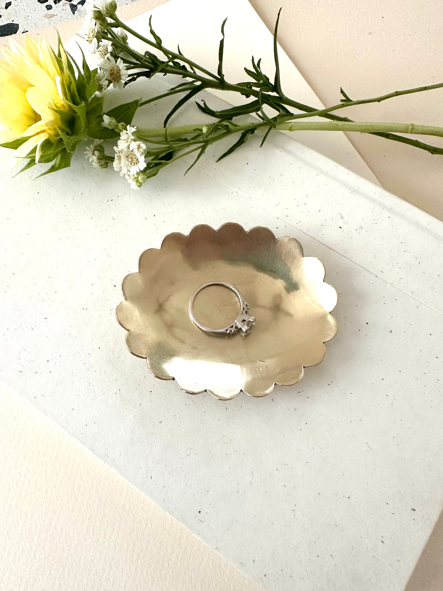 Sarah Cecelia Brass Ring dish with scallop edge and a diamond ring on a neutral background with florals