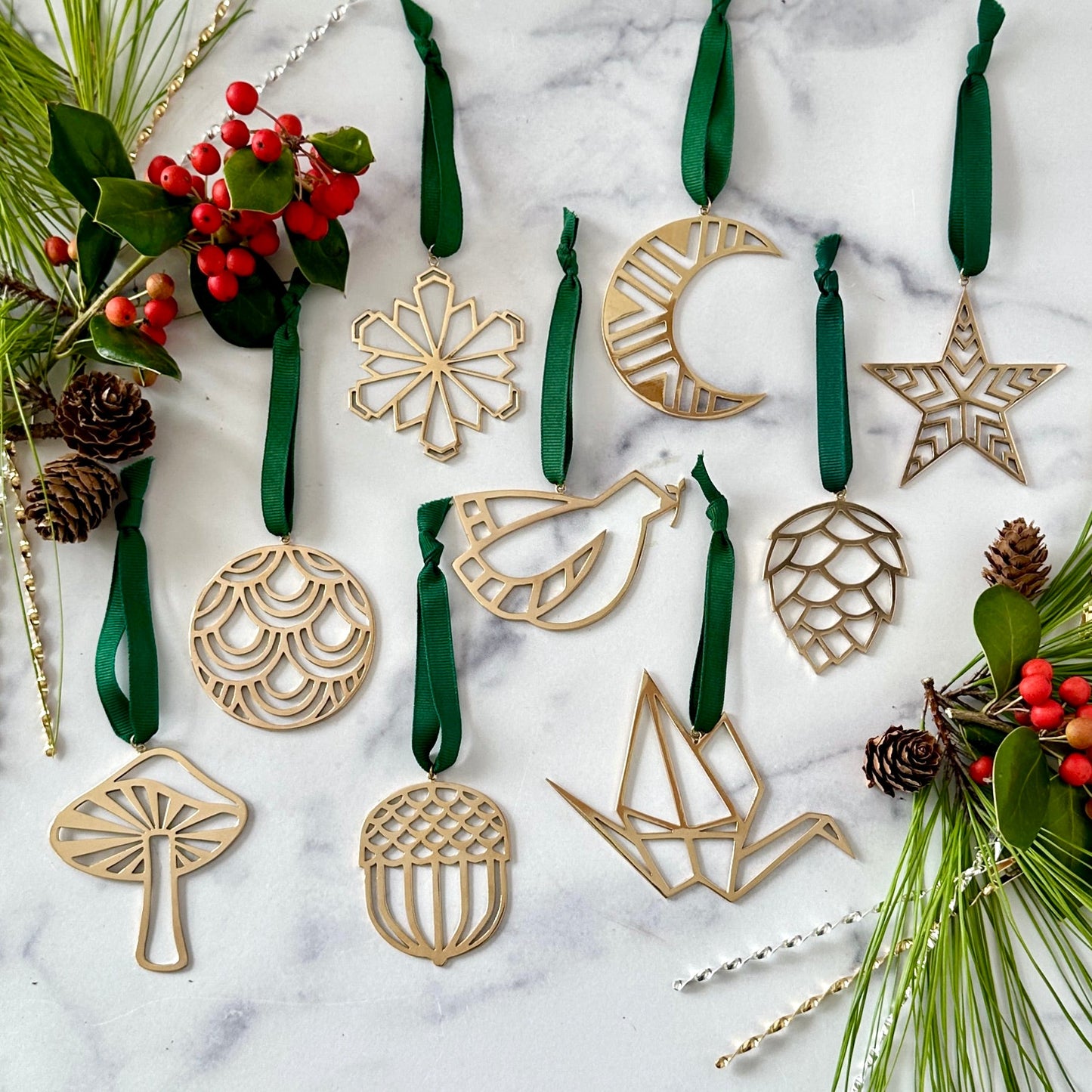 Decorative Christmas ornaments on a marble surface with greenery and berries.