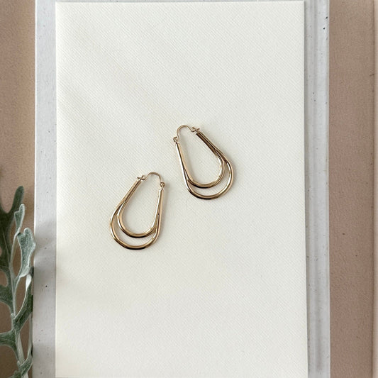 Gold hoop earrings on a white card with a minimal background
