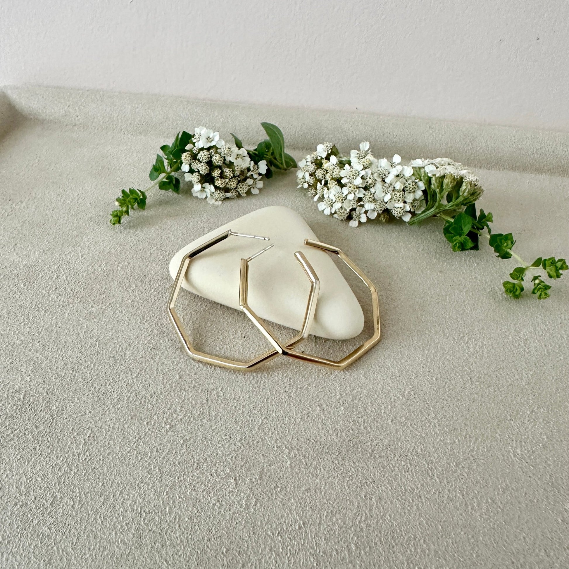 Gold Hoop earrings  geometric design on a textured surface with flowers.