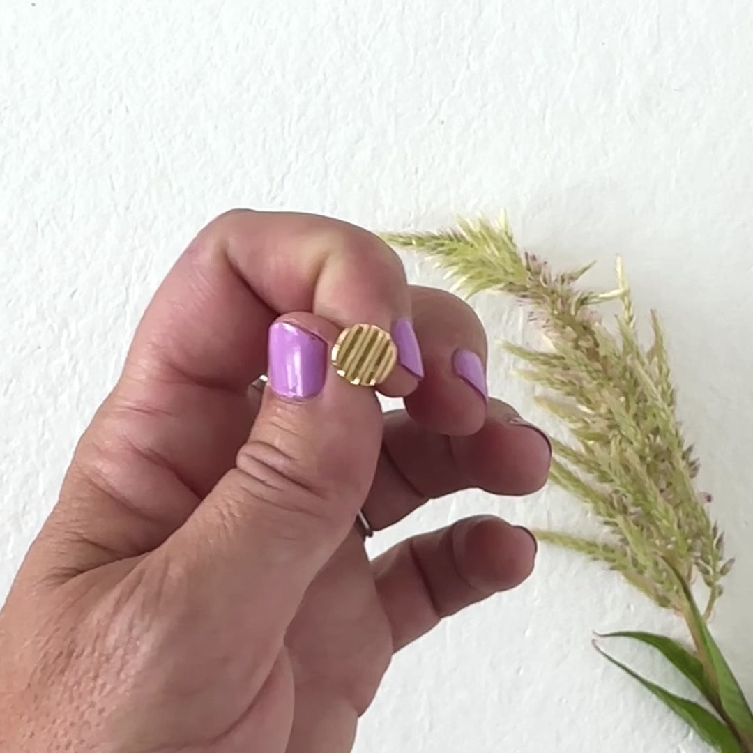 hand modeling gold disc stud earrings with neutral background