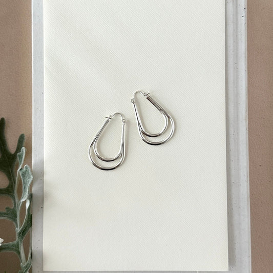 Pair of silver hoop earrings on a white card with a neutral background