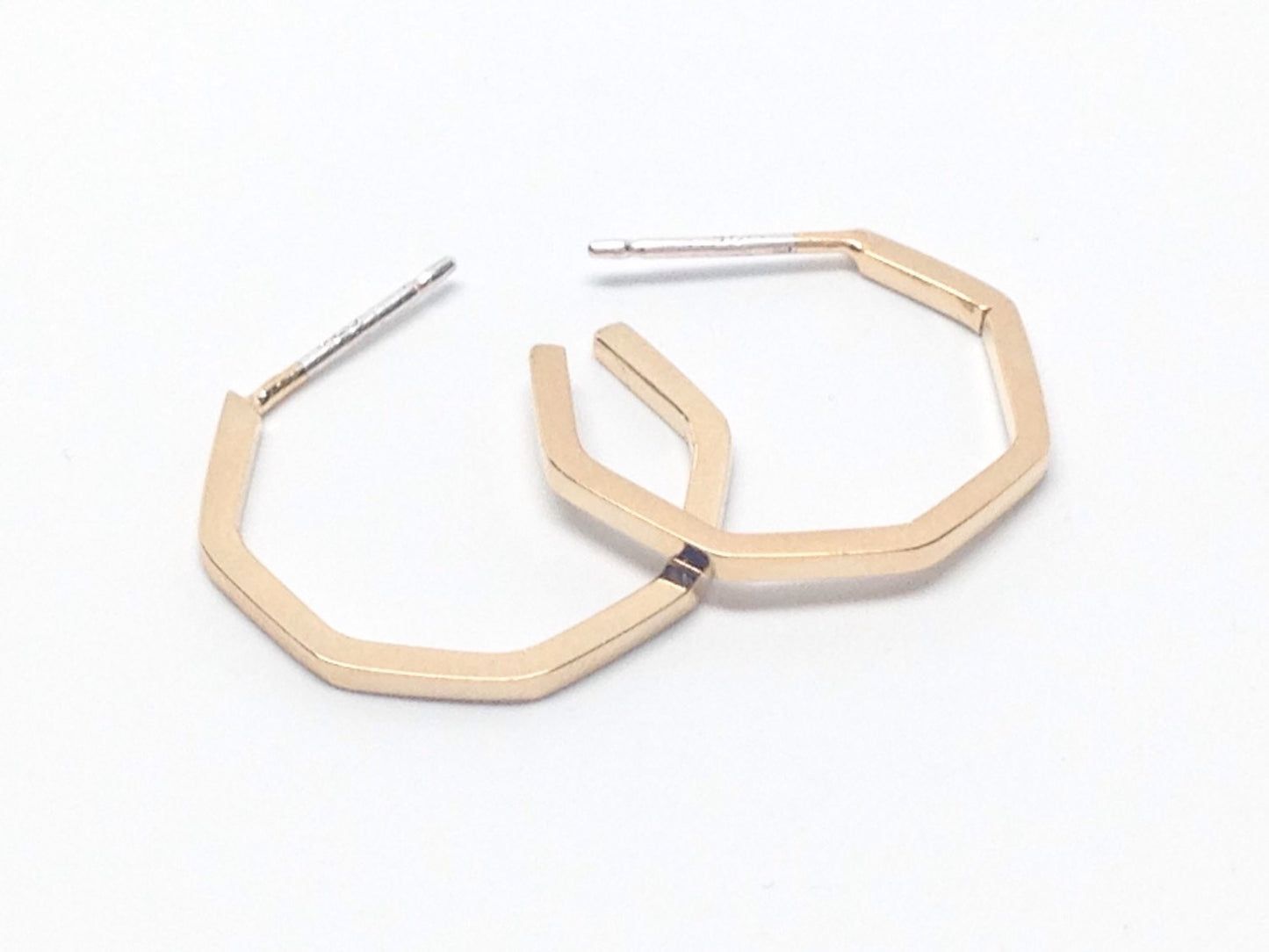 A pair of small gold plated geo hoops on a white background