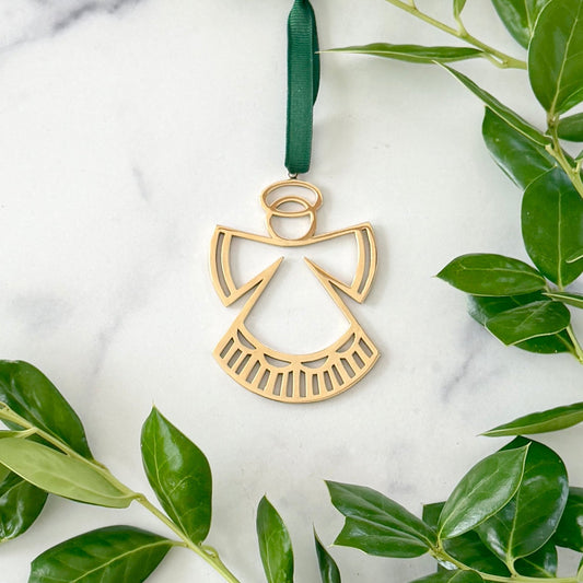 Brass Angel Ornament on a white background with greenery