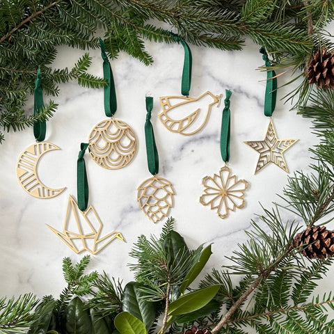 A collection of handmade brass ornaments displayed on a marble background with greenery 