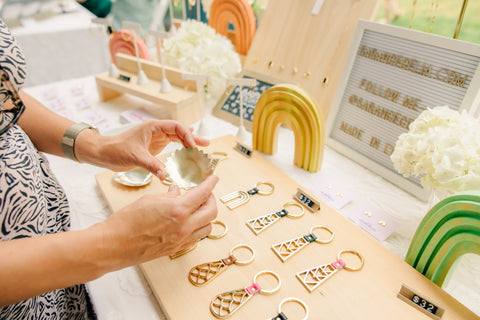 A display of handcrafted jewelry and metal goods with hands holding a jewelry dish 