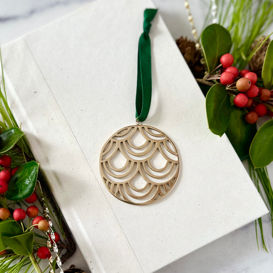 Decorative ornament with a green ribbon on a white box surrounded by greenery and berries.