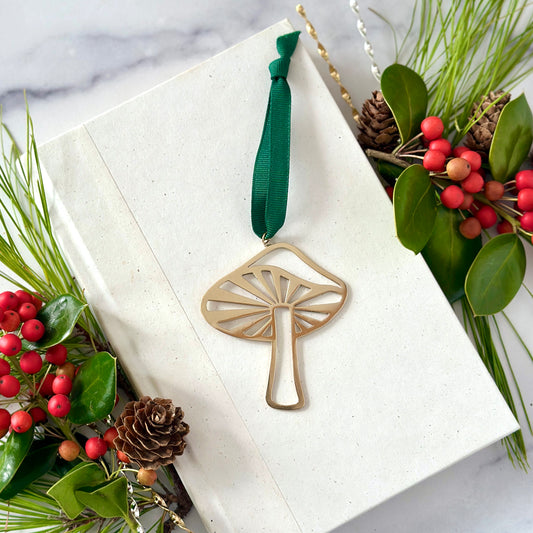 Decorative mushroom ornament on a white card with greenery and berries
