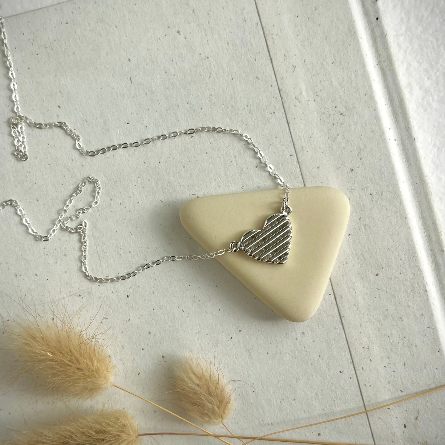 a sterling silver heart necklace on a neutral background 