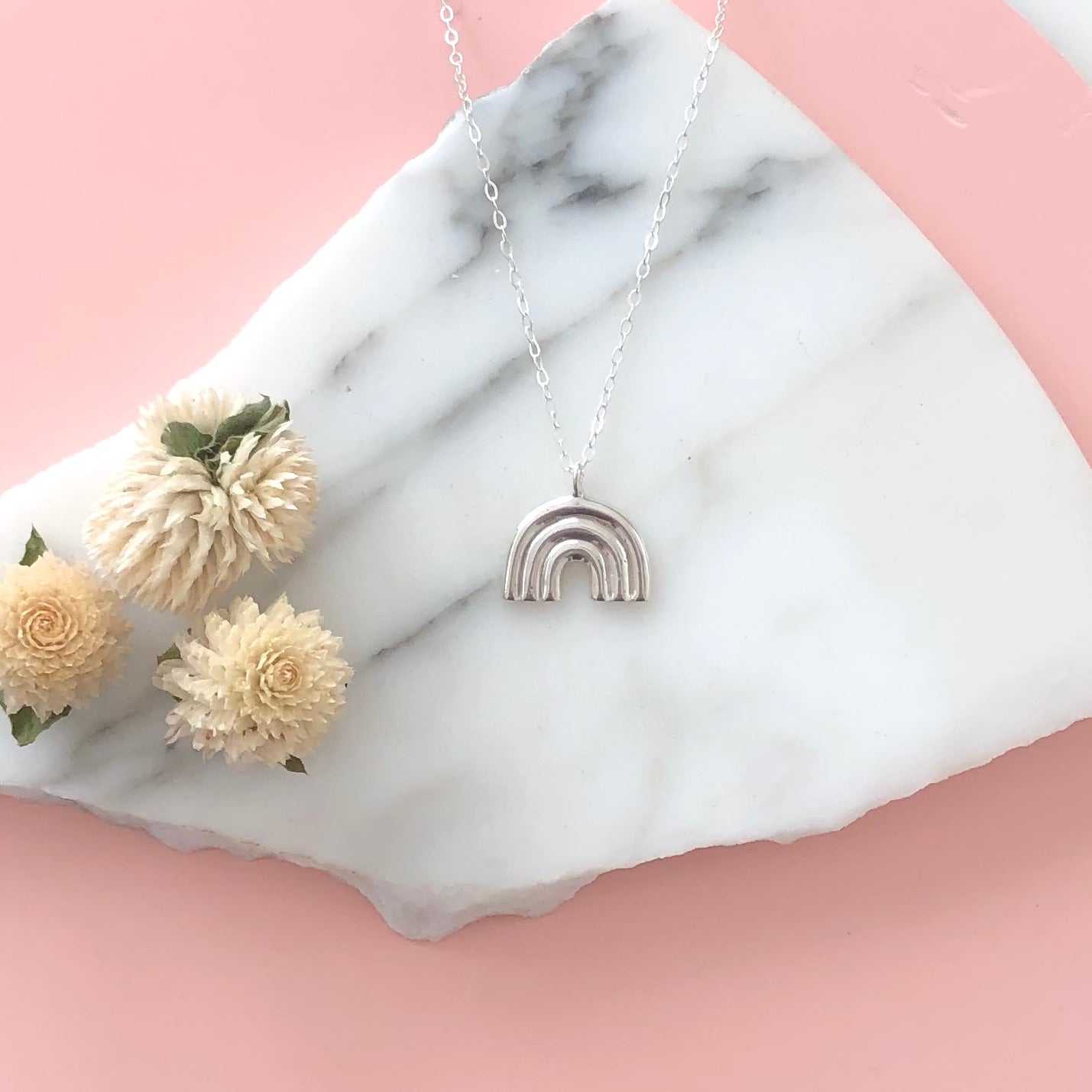 Sterling Silver Arco Necklace displayed on a piece of marble a circular marble background