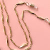 Shiny gold faceted eyeglass chain on a pink background by Sarah Cecelia 