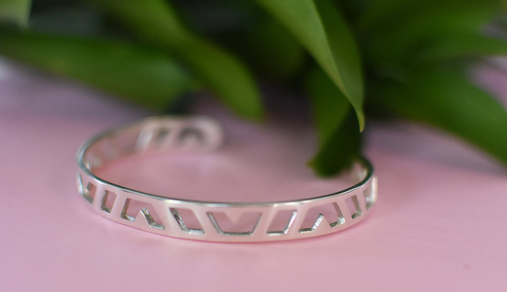 Sterling Silver carved cuff bracelet with a pink background and greenery 