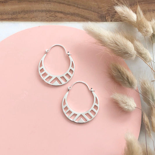Handmade Sterling Silver Spectra Hoop earrings on a pink and white background with dried flowers  