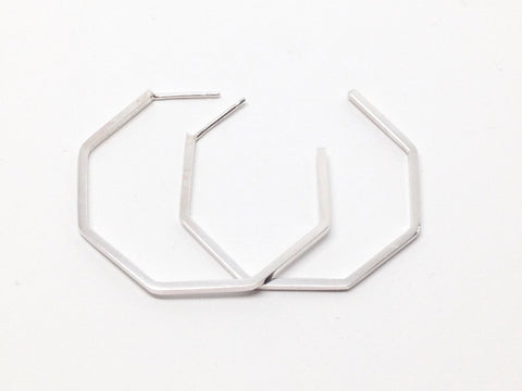 A pair of handmade sterling silver geometric hoop earrings on a white background 