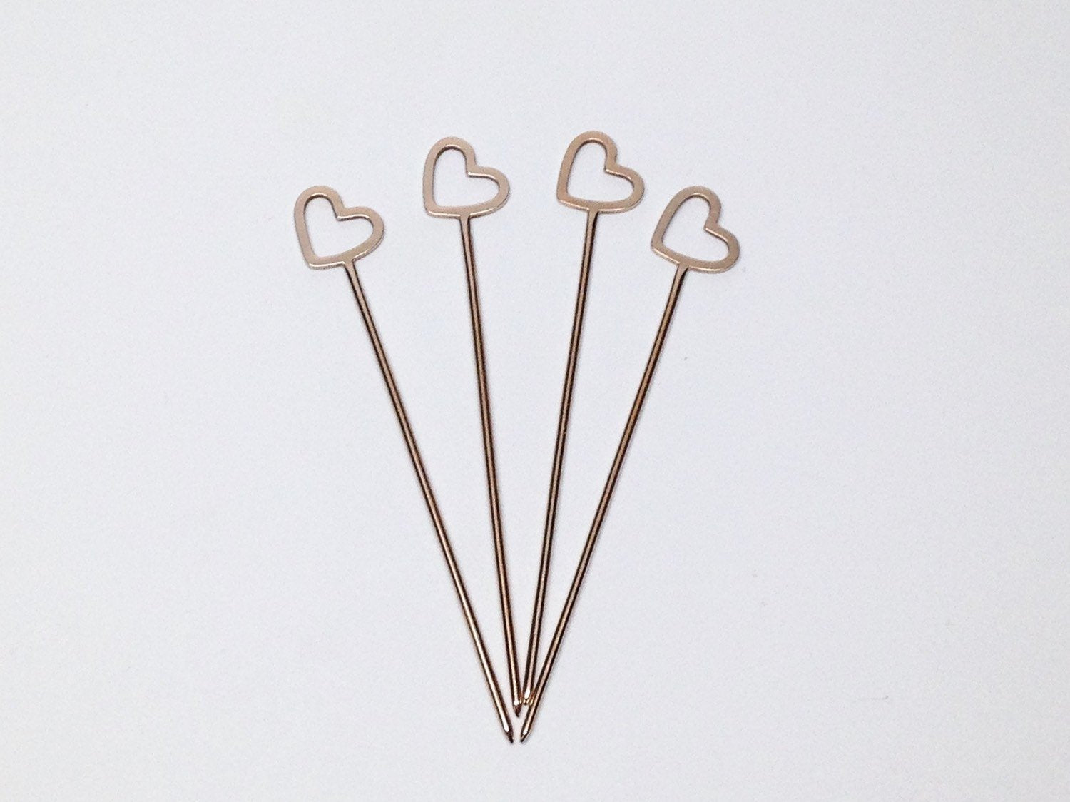 four gold plated brass cocktail picks on a white background 
